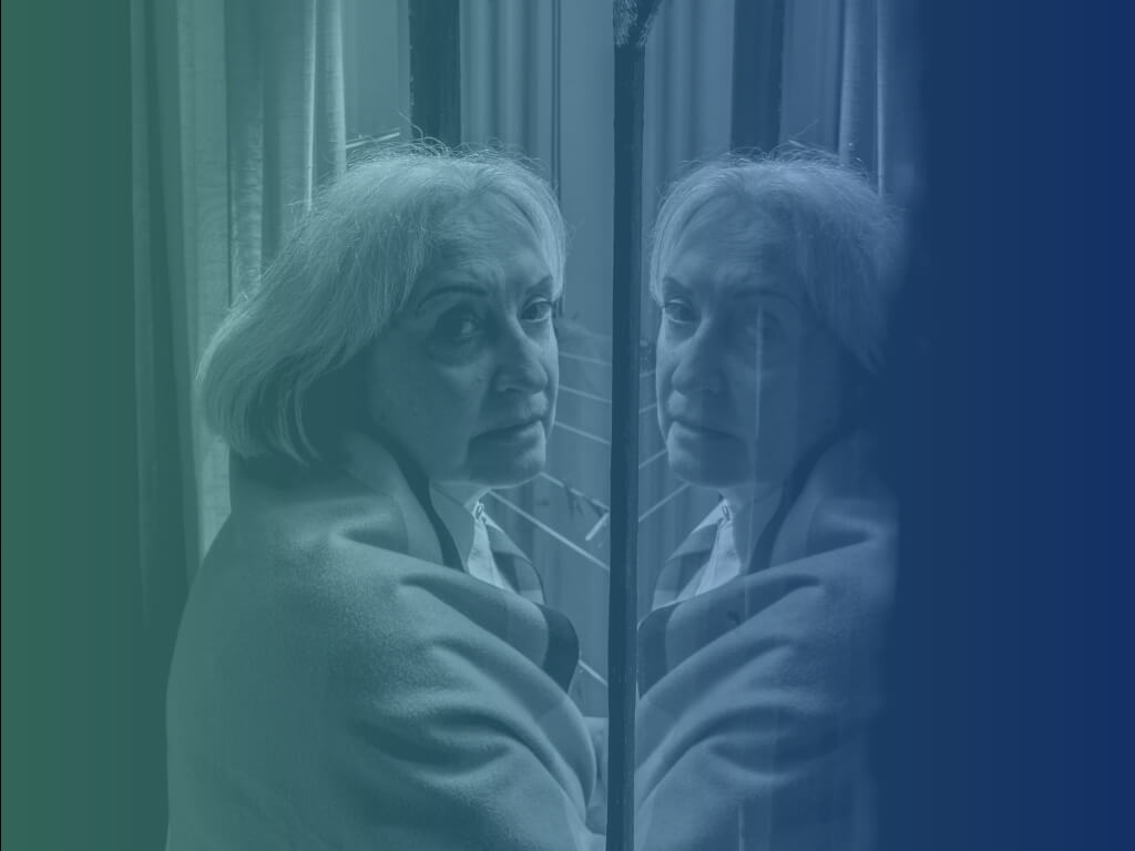 Older woman glancing back with a worried look beside a window, illustrating signs it may be time for dementia care